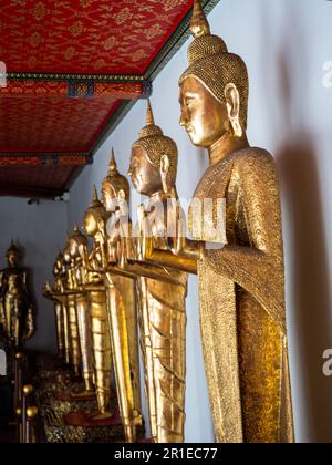 Une rangée de statues de Bouddha doré debout borde le mur du temple Wat Pho à Bangkok, en Thaïlande. Banque D'Images