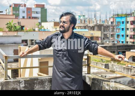Beau jeune homme en noir kabli panjabi robe debout sur le toit Banque D'Images