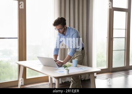 Un homme sérieux, jeune propriétaire de petite entreprise, travaille sur un ordinateur portable Banque D'Images