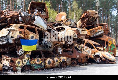 Le drapeau national de l'Ukraine sur fond de ruines et de métal rouillé de voitures détruites. Un drapeau bleu-jaune agitant dans le vent sous le soleil dedans Banque D'Images