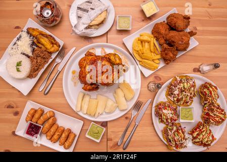 Plats de cuisine latino avec poulet rôti, poulet grillé, patacones avec sauces, yucca frit, rôti de bœuf et viande et arepas déchiquetés Banque D'Images