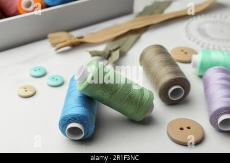 Couture de fils et de boutons sur une table en marbre blanc, gros plan Banque D'Images