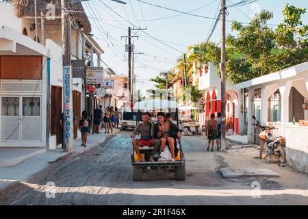 Les touristes montent une voiturette de golf dans les rues boueuses de Isla Holbox, au Mexique Banque D'Images