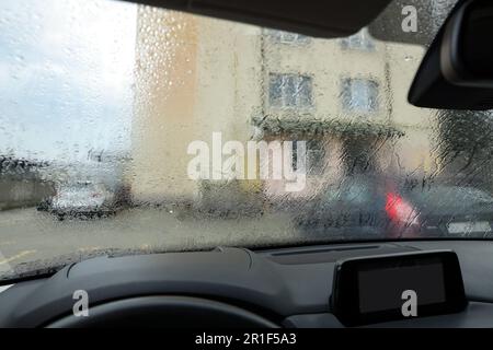 Vue sur la rue depuis le pare-brise de voiture moderne avec gouttes de pluie, gros plan Banque D'Images