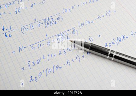 Papier avec calculs mathématiques écrits et stylo, gros plan Banque D'Images