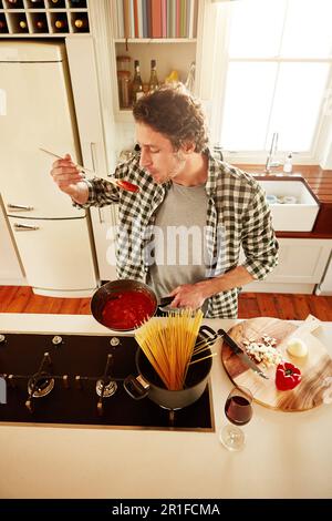 Nourriture, cuisine ou dégustation d'homme dans la cuisine avec un régime végétalien sain pour la nutrition ou les légumes à la maison en Italie. Goût de sauce spaghetti, au-dessus ou à la personne Banque D'Images