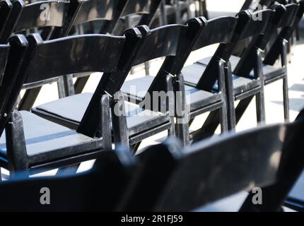 Rangée de chaises pliantes noires disposées en rangées pour un événement tel que mariage, funérailles, remise des diplômes, découpe de ruban, anniversaire, conférence, etc Photo de haute qualité Banque D'Images