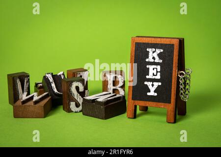 CLÉ, continuez à vous instruire concept. Tableau noir miniature et blocs d'alphabet sur fond vert. Banque D'Images