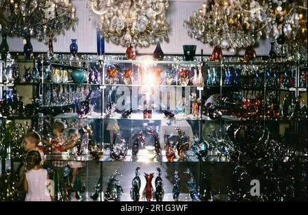 Deux jeunes enfants, un garçon et une fille, parcourir la verrerie dans un magasin de verre de Venise Italie ca. 1968 Banque D'Images