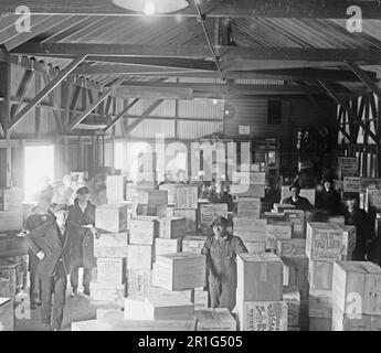 Photo archivistique : officiers se tenant dans un entrepôt parmi les cas de whisky confisqués ca. 1920s Banque D'Images