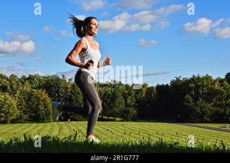Jeune femme courir dans le parc au cours de l'entraînement sportif Banque D'Images