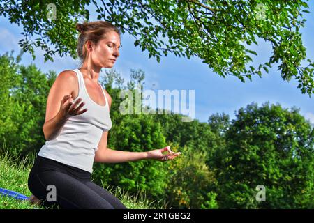 Jeune femme au cours de yoga méditation dans le parc Banque D'Images