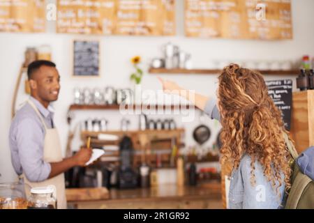 Femme, café et le menu sur le mur avec le barista, les notes et le service pour une bonne expérience client. Un serveur d'écriture, une dame et un homme qui parle Banque D'Images