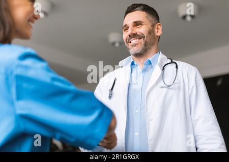 Joyeux médecin-chef de sexe masculin qui embauche un nouveau coéquipier à la clinique Banque D'Images