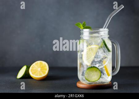 pot mason d'eau froide de détox avec concombre et citron sur fond gris Banque D'Images