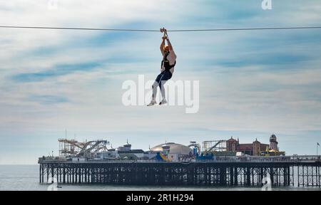 Un homme dans un harnais et portant un casque traverse la plage de Brighton en face de la célèbre jetée de Brighton et de son parc d'attractions. Brighton, a Banque D'Images