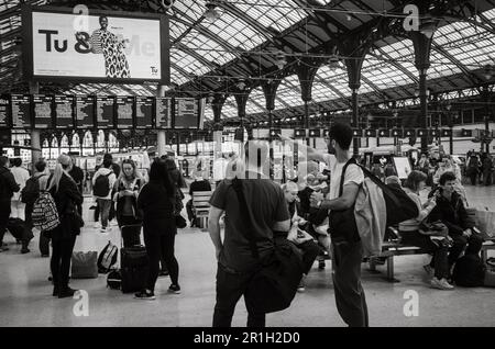 Passagers attendant sur le hall de la gare de Brighton à East Sussex, Royaume-Uni, alors qu'un seul homme pointe à la carte électronique des départs. Le victorien Banque D'Images