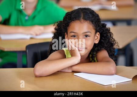 Portrait, enfant et étudiant ennuyé en classe avec livre, prêt à apprendre et à étudier en classe. L'ennui, l'éducation et la sérieuse fille indienne apprenant dans Banque D'Images