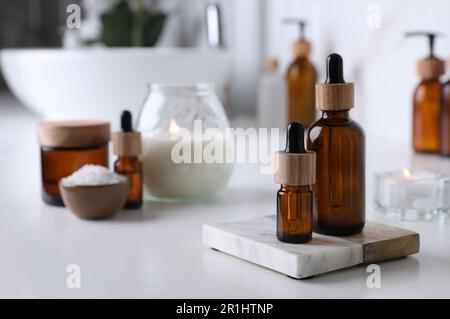 Huiles essentielles et autres produits cosmétiques sur comptoir blanc dans la salle de bains Banque D'Images