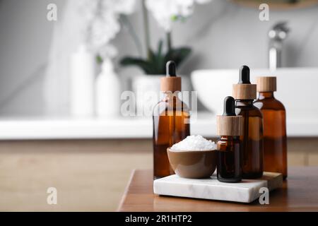 Huiles essentielles et sel de mer sur table en bois dans la salle de bains. Espace pour le texte Banque D'Images
