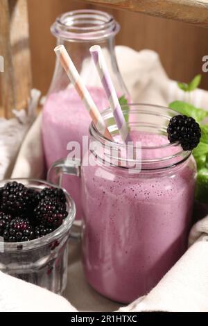 Différents verres de délicieux smoothie blackberry et de baies fraîches sur fond de bois, gros plan Banque D'Images