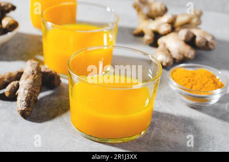 Doses de curcuma, boisson saine avec du curcuma et des épices, jus de Jamu, boisson de renforcement d'immunité sur fond gris clair Banque D'Images