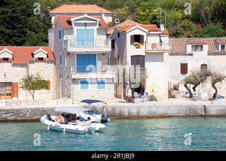 Prvic Luka, Croatie - 22 juillet 2022 : maisons en pierre au bord de la mer et un bateau en caoutchouc arrivant au quai Banque D'Images