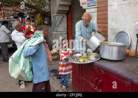 Jeune fille attendant la nourriture gratuite distribuée par un ouvrier de charité à Paharganj, New Delhi, Inde Banque D'Images