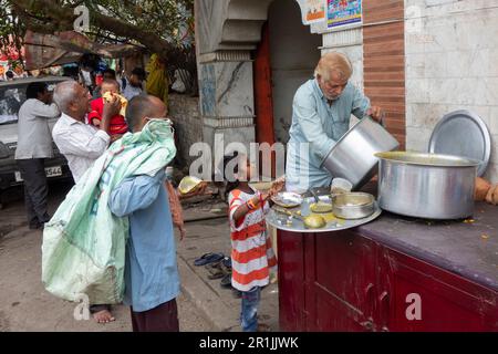 Jeune fille attendant la nourriture gratuite distribuée par un ouvrier de charité à Paharganj, New Delhi, Inde Banque D'Images