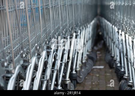 Deux rangées de chariots de supermarché en métal qui dans une rue se rencontrent à l'arrière. Faible profondeur de champ Banque D'Images