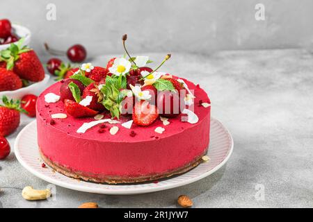 Gâteau aux fruits frais à la noix de cajou avec fraises fraîches et cerises dans une assiette. Dessert végétalien Banque D'Images