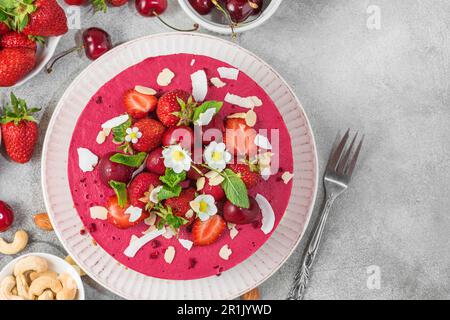 Dessert végétalien. Gâteau aux fruits frais à la noix de cajou avec fraises fraîches, cerises et noix dans une assiette. Vue de dessus Banque D'Images