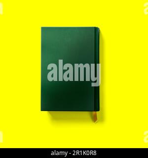 Retour à l'école concept , couverture rigide vert foncé livre arrière fermé isolé sur jaune. Banque D'Images