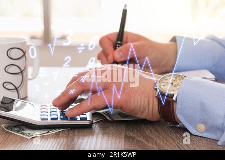 Les mains d'un homme caucasien méconnaissable en appuyant sur les boutons d'une calculatrice au-dessus d'une table en bois pendant qu'il écrit avec un stylo. Nombres et caractères Banque D'Images