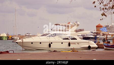 Moulins médiévaux en pierre avec toits rouges dans le port de Rhodes. Les yachts à moteur et à voile sont amarrés au remblai, dans la baie de Mandraki.drapeau grec sur un navire Banque D'Images