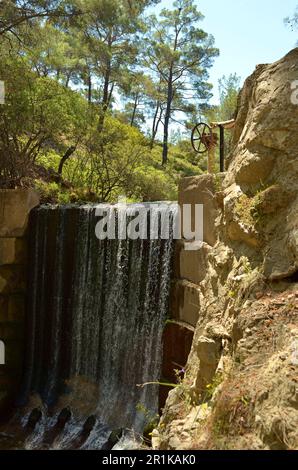 Une cascade artificielle parmi les grands arbres de la réserve naturelle sur l'île de Rhodes.High rock près de la cascade. Banque D'Images