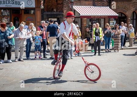 Lymm May Queen et Rose Queen 2023. Un artiste de rue qui roule sur un monocycle avec une poignée et une roue avant séparées Banque D'Images