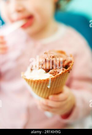 une petite fille tient un cône de crème glacée en gros plan Banque D'Images