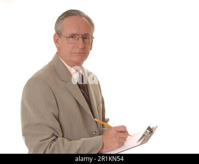 Homme d'affaires senior prenant des notes sur un presse-papiers Banque D'Images