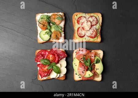 Toasts savoureux avec différentes garnitures sur table noire, plat Banque D'Images