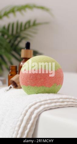 Serviette avec bombe de bain et bouteilles d'huiles essentielles sur la baignoire à l'intérieur Banque D'Images