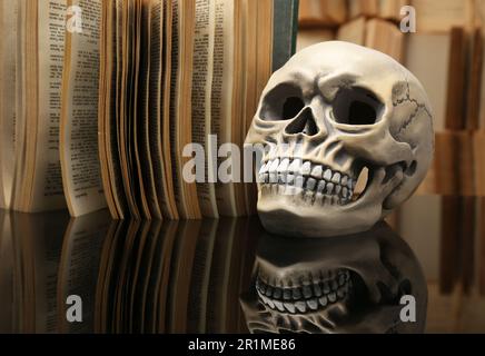 Crâne humain et vieux livre sur table miroir Banque D'Images