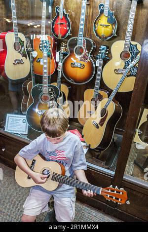 Sevierville Tennessee, Music Outlet magasin d'affaires instruments de musique vente shopping, intérieur garçon essayant de jouer de la guitare d'enfant, guitares affichage, Banque D'Images