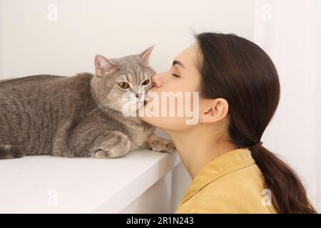 Jeune femme embrassant son adorable chat à la maison Banque D'Images