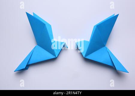 Magnifiques oiseaux d'origami bleu sur fond blanc, plat. Banque D'Images