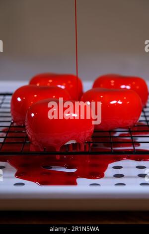 Le chef pâtissier verse des gâteaux au sirop de baies rouges liquide sur une grille de refroidissement. Le chef pâtissier prépare des gâteaux de mousse. 4K images de haute qualité Banque D'Images