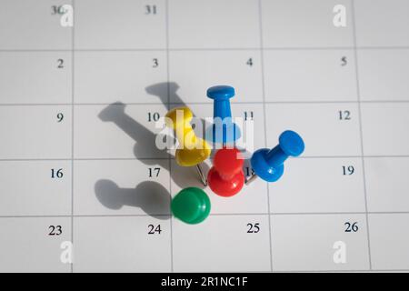 Codes PIN multicolores sur une date d'un calendrier. Concept d'horaire occupé et complet. Banque D'Images