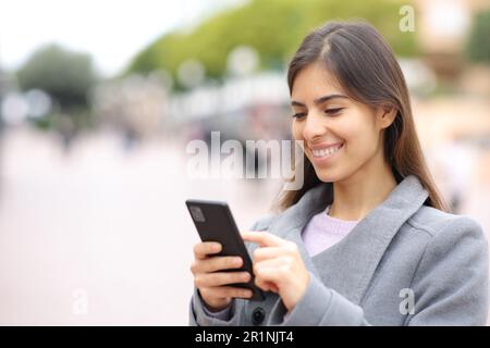 Bonne femme utilisant un téléphone cellulaire en hiver dans la rue Banque D'Images