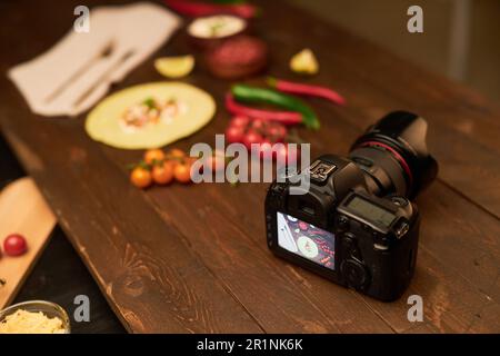 Vue en grand angle de l'appareil photo numérique sur la table pour réaliser des photos professionnelles avec des aliments en arrière-plan Banque D'Images