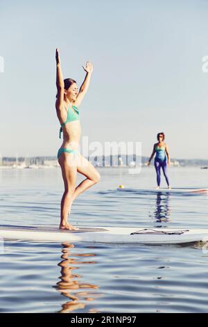 Deux femmes font du yoga sur les panneaux SUP tôt le matin Banque D'Images